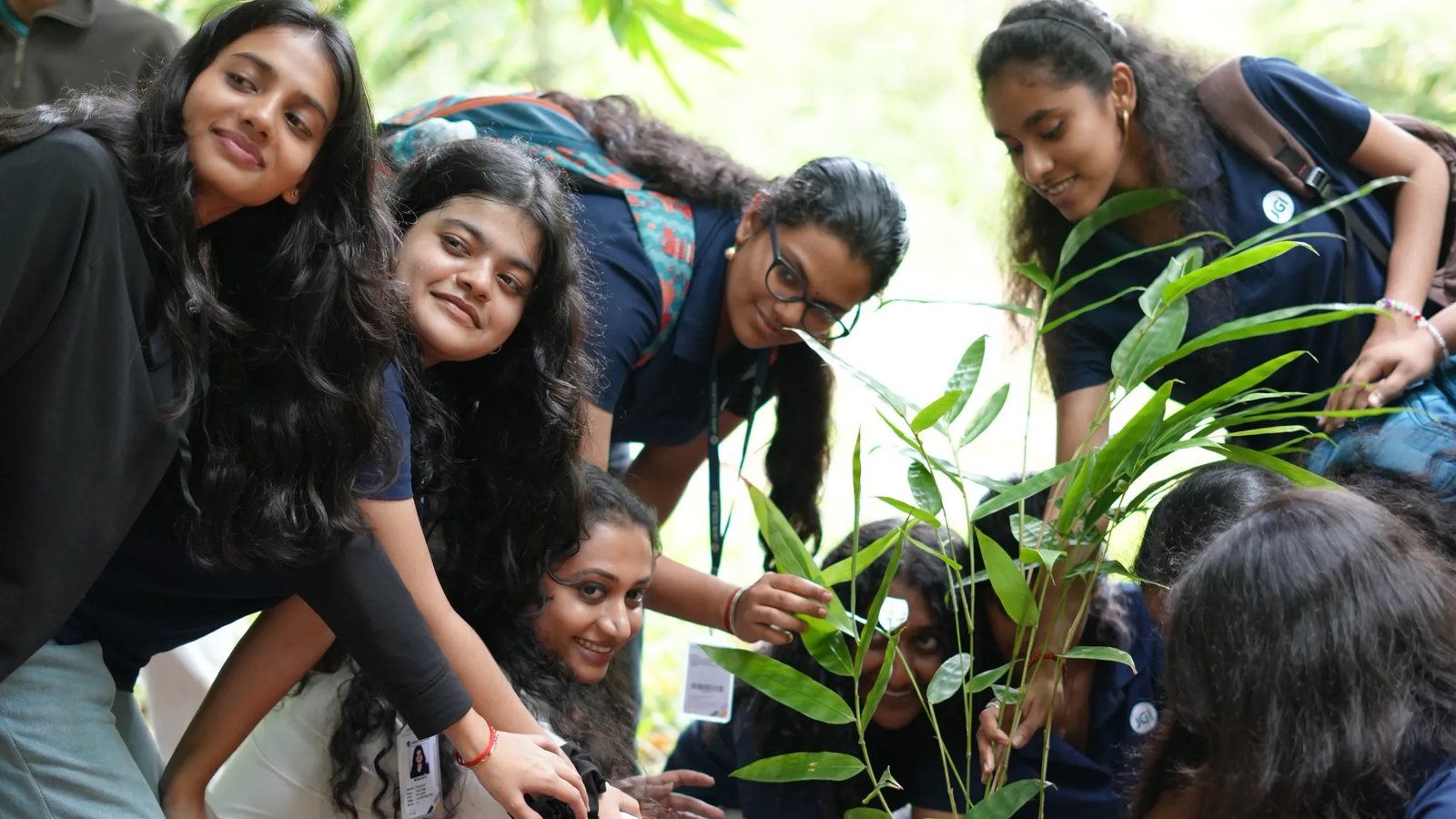 Girls smiling while planting a tree at Young Harvesters